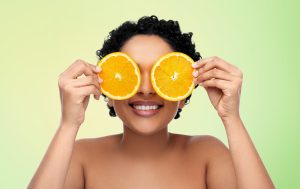 Girl holding sliced orange over her eyes